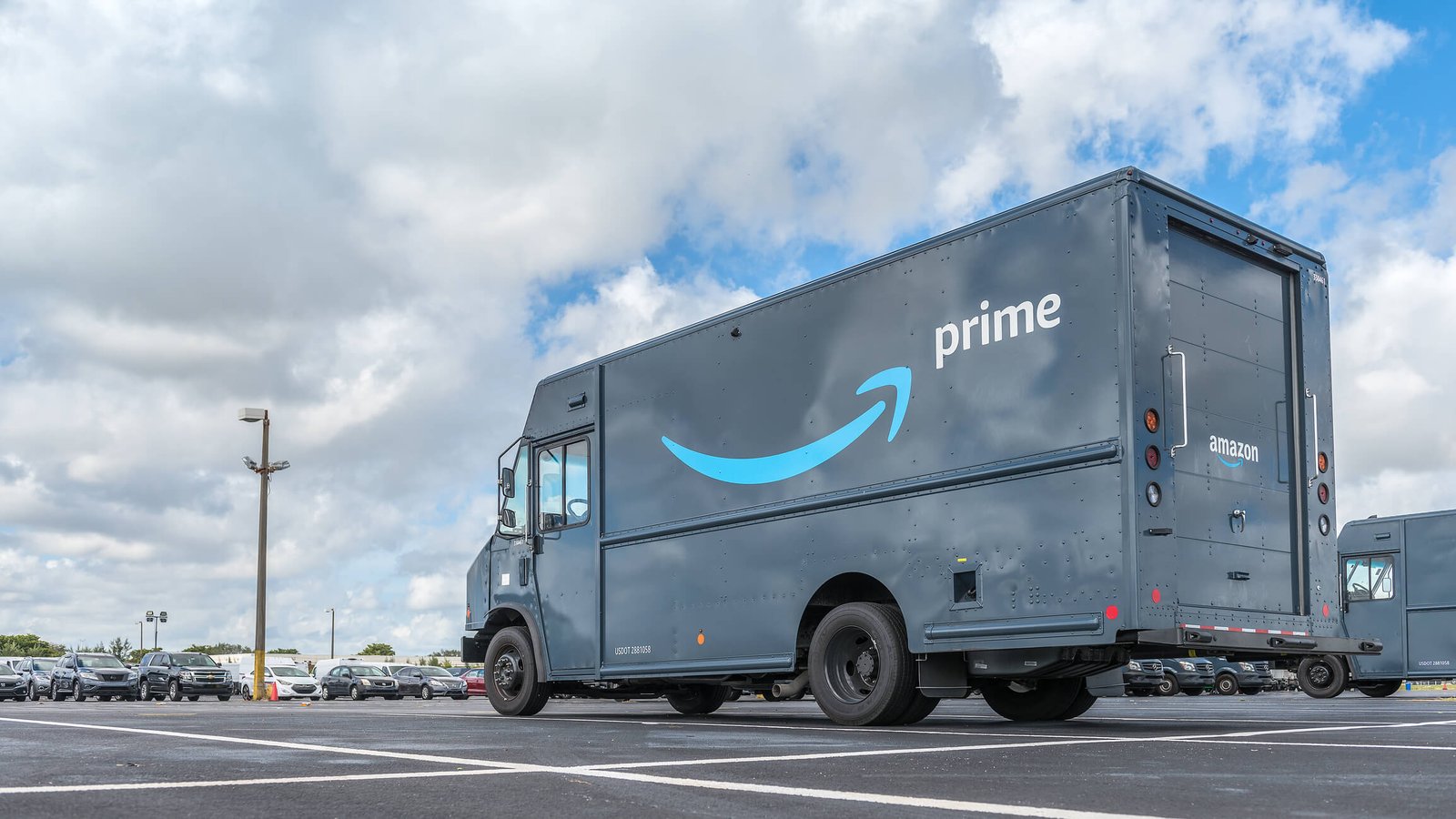 An unmarked Amazon Prime delivery truck parked in a sunny parking lot under blue sky.